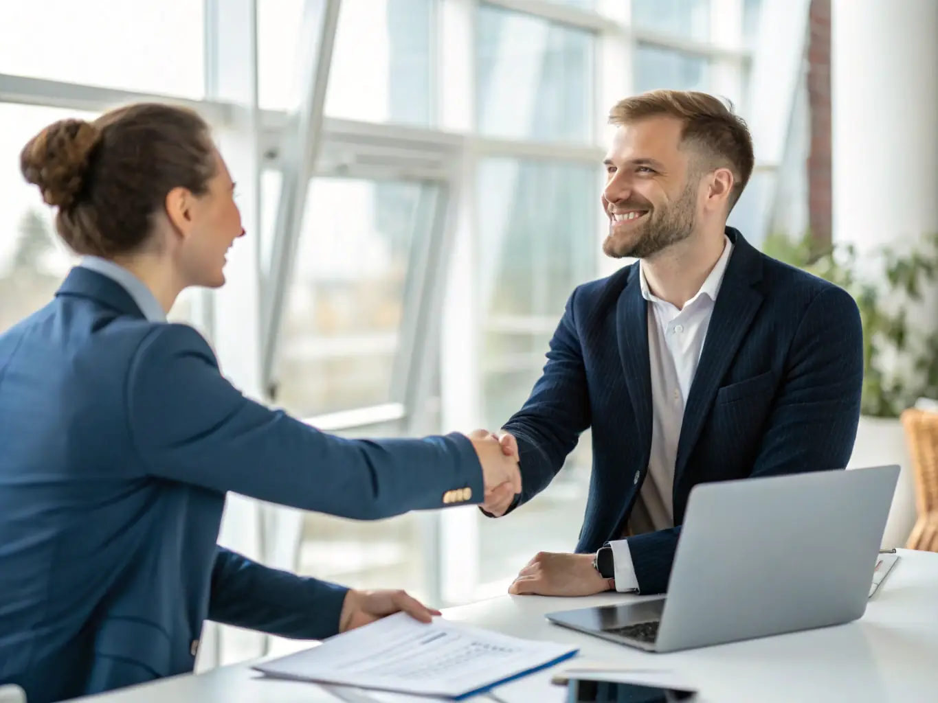 A professional recruiter in a modern office setting, shaking hands with a client, symbolizing a successful partnership and the beginning of a talent acquisition process.